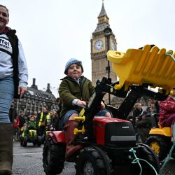 Los niños montan tractores de juguete frente a la Torre Elizabeth, conocida comúnmente por el nombre de la campana del reloj "Big Ben", en el Palacio de Westminster, hogar de las Cámaras del Parlamento, durante una protesta de agricultores contra los cambios en las reglas del impuesto a la herencia para la propiedad de la tierra, en Londres. | Foto:Ben Stansall / AFP