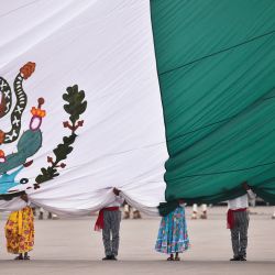 Miembros del ejército mexicano vestidos como soldados revolucionarios sostienen la bandera nacional durante la conmemoración del 114 aniversario de la Revolución Mexicana en la plaza del Zócalo de la Ciudad de México. | Foto:Rodrigo Oropeza / AFP