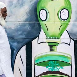 Un hombre pasa junto a un mural pintado para crear conciencia sobre el problema de la contaminación del aire en Varanasi, India. | Foto:NIHARIKA KULKARNI / AFP