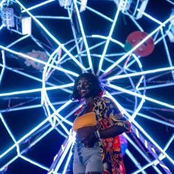 Una mujer se encuentra de pie frente a una noria mientras asiste al tercer día del Festival Nyege Nyege en Jinja, Uganda. | Foto:BADRU KATUMBA / AFP