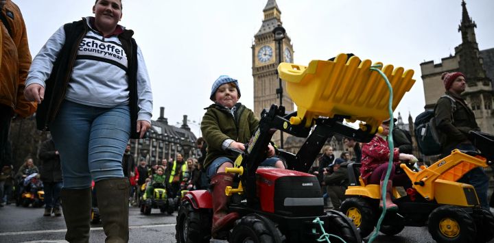 Los niños montan tractores de juguete frente a la Torre Elizabeth, conocida comúnmente por el nombre de la campana del reloj "Big Ben", en el Palacio de Westminster, hogar de las Cámaras del Parlamento, durante una protesta de agricultores contra los cambios en las reglas del impuesto a la herencia para la propiedad de la tierra, en Londres.