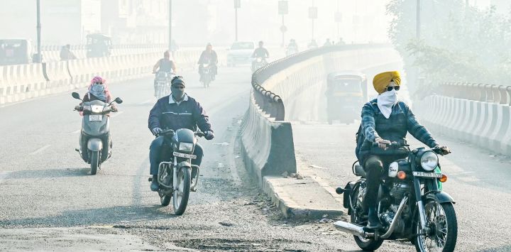 Los viajeros con el rostro cubierto con tela recorren una calle en medio de una espesa niebla en Amritsar, India.