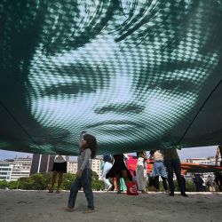 Manifestantes sostienen una imagen gigante del activista ambiental brasileño Txai Surui para instar a los líderes mundiales a proteger el medio ambiente y defender la selva amazónica, en la playa de Botafogo en Río de Janeiro. | Foto:LUIS ROBAYO / AFP