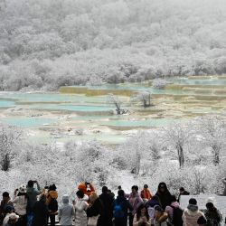 Turistas observan un grupo de estanques coloridos en el área escénica de Huanglong después de una nevada, en la prefectura autónoma tibetana de Qiang, en la provincia de Sichuan, en el suroeste de China. | Foto:Xinhua/Liu Lianfen