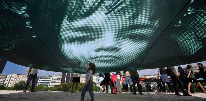 Manifestantes sostienen una imagen gigante del activista ambiental brasileño Txai Surui para instar a los líderes mundiales a proteger el medio ambiente y defender la selva amazónica, en la playa de Botafogo en Río de Janeiro.