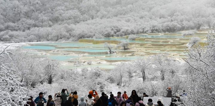 Turistas observan un grupo de estanques coloridos en el área escénica de Huanglong después de una nevada, en la prefectura autónoma tibetana de Qiang, en la provincia de Sichuan, en el suroeste de China.