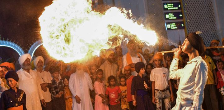 Un joven sij realiza un acto de lanzamiento de fuego durante una procesión religiosa en vísperas del aniversario del nacimiento de Guru Nanak Dev (fundador del sijismo) en Patna, en el estado indio de Bihar.