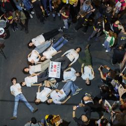 Manifestantes simulan estar muertos durante una protesta antigubernamental para exigir la liberación de los israelíes tomados como rehenes por militantes palestinos en Gaza desde los ataques de octubre de 2023, frente al Ministerio de Defensa en Tel Aviv, en medio de la guerra en curso entre Israel y el grupo militante palestino Hamás. | Foto:JACK GUEZ / AFP