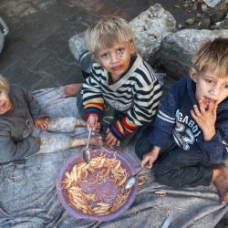 Niños palestinos comparten un plato de comida en su tienda de campaña para desplazados en el campo de refugiados de Bureij, en el centro de la Franja de Gaza, en medio de la guerra en curso entre Israel y el grupo militante palestino Hamás. | Foto:Eyad Baba / AFP