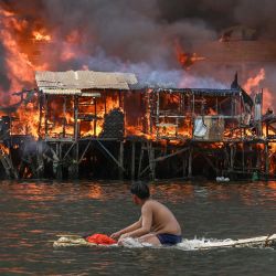Un hombre observa las casas en llamas en Tondo, Manila. Furiosas llamas anaranjadas y un espeso humo negro se elevaban hacia el cielo, mientras el fuego arrasaba cientos de casas en una zona marginal de la capital filipina, Manila. | Foto:JAM STA ROSA / AFP