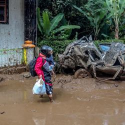 Una familia camina por el barro y pasa junto a un automóvil aplastado tras los deslizamientos de tierra en la aldea Semangat Gunung en Karo, en el norte de Sumatra. Las inundaciones repentinas y un deslizamiento de tierra arrasaron cuatro distritos de la isla indonesia de Sumatra durante el fin de semana, matando al menos a 16 personas, dijo la agencia nacional de desastres. | Foto:KIKI CAHYADI / AFP