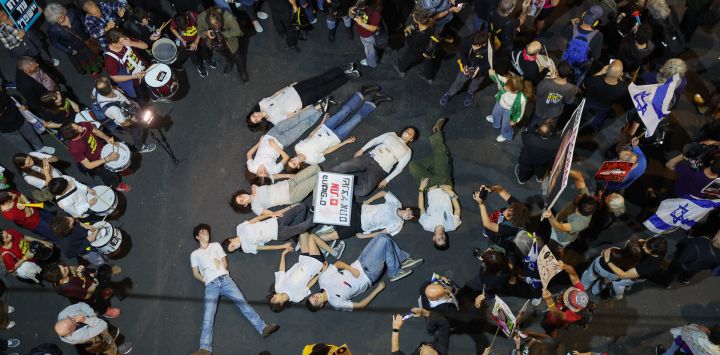 Manifestantes simulan estar muertos durante una protesta antigubernamental para exigir la liberación de los israelíes tomados como rehenes por militantes palestinos en Gaza desde los ataques de octubre de 2023, frente al Ministerio de Defensa en Tel Aviv, en medio de la guerra en curso entre Israel y el grupo militante palestino Hamás.