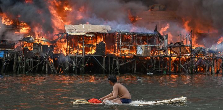 Un hombre observa las casas en llamas en Tondo, Manila. Furiosas llamas anaranjadas y un espeso humo negro se elevaban hacia el cielo, mientras el fuego arrasaba cientos de casas en una zona marginal de la capital filipina, Manila.