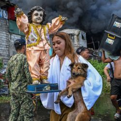 Los residentes llevan sus pertenencias durante un incendio en Tondo, Manila. Las llamas anaranjadas y el humo negro y espeso se elevaban hacia el cielo mientras el fuego arrasaba cientos de casas en una zona marginal de la capital filipina, Manila, que está muy cerca de la capital. | Foto:JAM STA ROSA / AFP