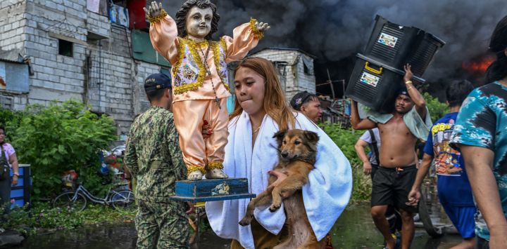 Los residentes llevan sus pertenencias durante un incendio en Tondo, Manila. Las llamas anaranjadas y el humo negro y espeso se elevaban hacia el cielo mientras el fuego arrasaba cientos de casas en una zona marginal de la capital filipina, Manila, que está muy cerca de la capital.