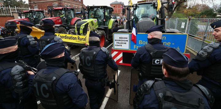 Oficiales del Cuerpo de Seguridad Republicano (CRS) de la policía nacional francesa se colocan delante de tractores mientras agricultores franceses participan en una manifestación organizada por la Coordinación Rural, un sindicato de agricultores, para protestar contra el acuerdo UE-Mercosur, en Estrasburgo, este de Francia.