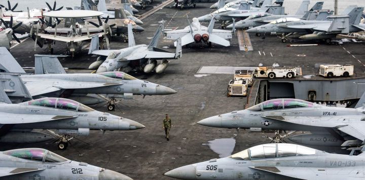 Un oficial de la Marina de los EE. UU. pasa junto a aviones de combate estacionados en la cubierta de vuelo del portaaviones USS Abraham de la clase Nimitz durante una gira de prensa en Port Klang, en las afueras de Kuala Lumpur.