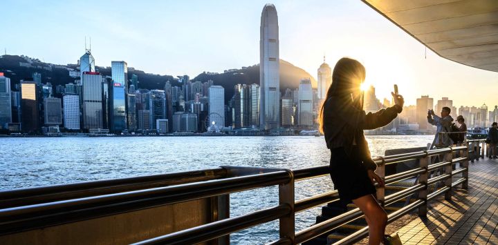 Una mujer se toma una selfie frente al horizonte de Hong Kong.