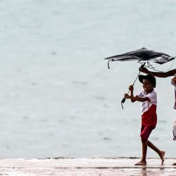 Una mujer ayuda a un niño a sostener su paraguas mientras caminan en medio de un fuerte aguacero en Colombo, Sri Lanka. | Foto:ISHARA S. KODIKARA / AFP