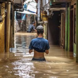 Un hombre camina entre las aguas de la inundación provocada por el desbordamiento de un río tras las fuertes lluvias en Yakarta, Indonesia. | Foto:BAY ISMOYO / AFP