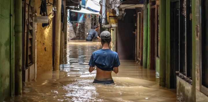 Un hombre camina entre las aguas de la inundación provocada por el desbordamiento de un río tras las fuertes lluvias en Yakarta, Indonesia.