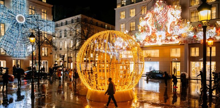 Un peatón camina junto a las luces navideñas en la calle Faubourg-Saint-Honoré, en París, Francia.