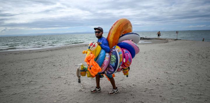 Un vendedor camina en la playa El Yaque en la isla de Margarita, estado Nueva Esparta, Venezuela. Margarita, la principal isla de Venezuela, es un paraíso caribeño en decadencia tras años de devaluaciones, inflación, pandemia y colapso de los servicios públicos.