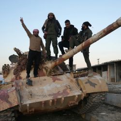 Los combatientes antigubernamentales posan para una fotografía en un tanque en la carretera que conduce a Maaret al-Numan, en la provincia de Idlib, en el noroeste de Siria. Los rebeldes liderados por los yihadistas tomaron el aeropuerto de Alepo y decenas de ciudades cercanas, después de invadir la mayor parte de la segunda ciudad de Siria, Alepo, dijo el Observatorio Sirio de Derechos Humanos. | Foto:MUHAMMAD HAJ KADOUR / AFP