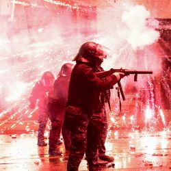 Los fuegos artificiales lanzados por los manifestantes explotan cerca de la policía antidisturbios que dispara gases lacrimógenos durante el cuarto día de protestas a nivel nacional contra la decisión del gobierno de suspender las negociaciones para la adhesión a la UE en Tbilisi. | Foto:GIORGI ARJEVANIDZE / AFP
