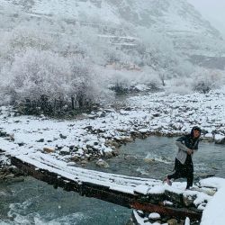 Un niño afgano cruza una pasarela durante la primera nevada en el distrito de Dara, en la provincia afgana de Panjshir. | Foto:Shah Poor Afzally / AFP
