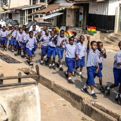 Los escolares ondean banderas de Ghana mientras participan en una caminata organizada para promover la paz antes de las elecciones presidenciales en Accra. | Foto:OLYMPIA DE MAISMONT / AFP)