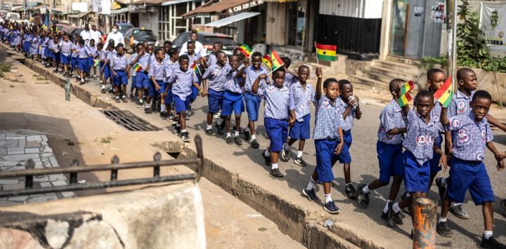 Los escolares ondean banderas de Ghana mientras participan en una caminata organizada para promover la paz antes de las elecciones presidenciales en Accra.