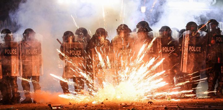 Los fuegos artificiales lanzados por los manifestantes explotan a lo largo de las líneas policiales mientras las dos partes se enfrentan durante una manifestación contra la decisión del gobierno de retrasar las conversaciones sobre la membresía de la Unión Europea en medio de una crisis poselectoral, fuera del Parlamento de Georgia en Tbilisi.