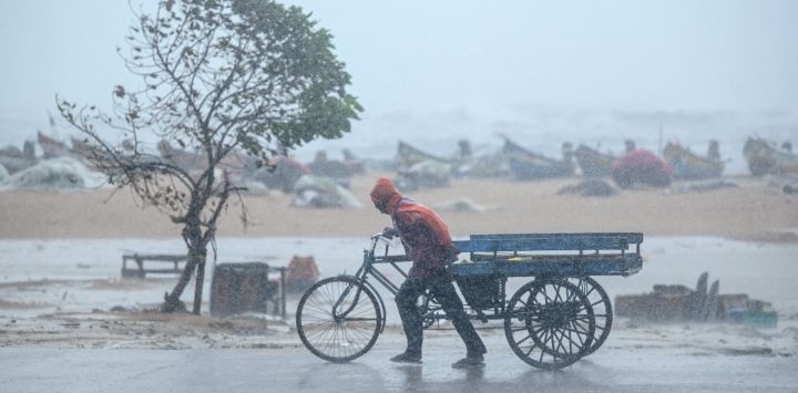 Un hombre tira de su carreta de tres ruedas en medio de fuertes vientos y lluvias en la playa Marina Beach en Chennai, antes de que el ciclón Fengal toque tierra en el estado de Tamil Nadu, en la India.