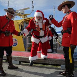 Imagen de miembros de la Real Policía Montada de Canadá ayudando a Papa Noel mientras desembarca de un bote en el muelle de pescadores de Steveston, en Richmond, Columbia Británica, Canadá. | Foto:Xinhua/Liang Sen