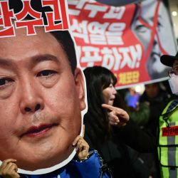Un manifestante sostiene una cartulina con la leyenda "Líder de los insurgentes" sobre una imagen que muestra el rostro del presidente de Corea del Sur, Yoon Suk Yeol, durante una protesta para pedir su destitución frente a la Asamblea Nacional en Seúl | Foto:Philip Fong / AFP