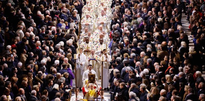 Miembros del clero y portadores de estandartes caminan hacia el nuevo altar principal durante su consagración, como parte de la primera misa para el público, en la catedral de Notre-Dame de París.