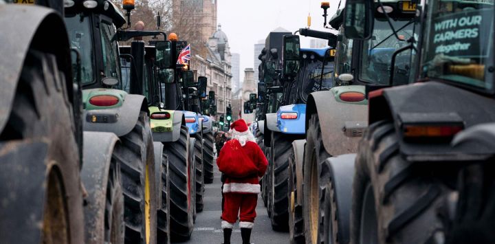 Una persona vestida de Papá Noel camina entre tractores estacionados a lo largo de Whitehall durante una manifestación para detener "la muerte de la agricultura británica", en protesta contra los cambios en las reglas del impuesto a la herencia para la propiedad de la tierra de los agricultores, en el centro de Londres.