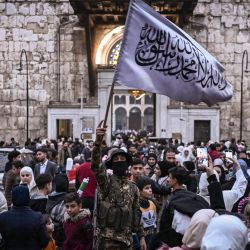Un combatiente ondea una bandera islámica en el mercado de Hamidiyeh, en la ciudad vieja de Damasco. Los rebeldes liderados por islamistas tomaron Damasco en una ofensiva relámpago, derrocando al presidente Bashar al-Assad y poniendo fin a cinco décadas de gobierno del partido Baath en Siria. | Foto:ARIS MESSINIS / AFP