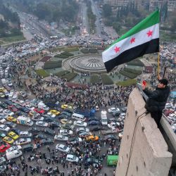 Una vista aérea muestra a un hombre sirio ondeando la bandera siria de la era de la independencia en la plaza central de los Omeyas de Damasco. | Foto:BAKR ALKASEM / AFP