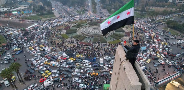 Una vista aérea muestra a un hombre sirio ondeando la bandera siria de la era de la independencia en la plaza central de los Omeyas de Damasco.