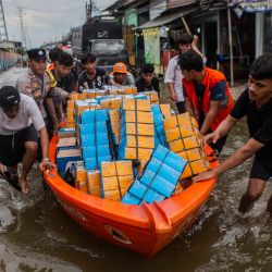 Los voluntarios llevan ayuda alimentaria en un bote mientras se desplazan a través de las aguas de la inundación provocada por la marea en Muara Angke, en Yakarta, Indonesia. | Foto:ADITYA AJI / AFP