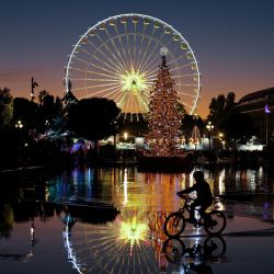 Un niño monta en bicicleta junto a una noria y un árbol de Navidad instalados en la ciudad de Niza, en la Riviera francesa. | Foto:Valery Hache / AFP