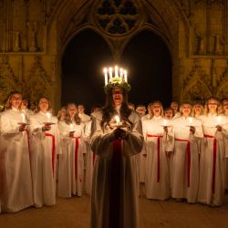 Alida Freding, de 19 años y oriunda de Estocolmo (centro), interpreta el papel de Lucía y está acompañada por el coro Chorus Pictor y amigos durante el servicio sueco 'Sankta Lucia Festival of Light' en la Catedral de York, en York, en el norte de Inglaterra. En Suecia, Lucía es una de las tradiciones más importantes del calendario: un poderoso símbolo y celebración de la luz y una parte integral de la temporada de Adviento.  | Foto:OLI SCARFF / AFP