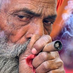 Un sadhu o santo hindú fuma un 'chillum', una pipa de arcilla tradicional, sentado en su tienda de campaña cerca del río Ganges, antes del festival Maha Kumbh Mela en Prayagraj, India. | Foto:MONEY SHARMA / AFP