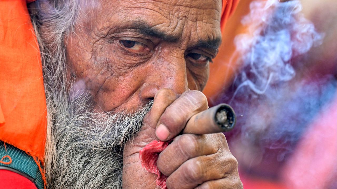 Un sadhu o santo hindú fuma un 'chillum', una pipa de arcilla tradicional, sentado en su tienda de campaña cerca del río Ganges, antes del festival Maha Kumbh Mela en Prayagraj, India. | Foto:MONEY SHARMA / AFP