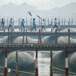Los trabajadores caminan sobre un puente flotante en las orillas del río Ganges, antes del festival Maha Kumbh Mela en Prayagraj, India. | Foto:MONEY SHARMA / AFP