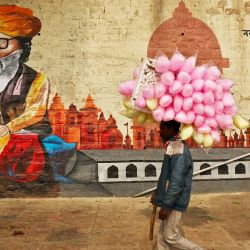 Un vendedor de algodón de azúcar pasa junto a un mural en las orillas del río Ganges en Bundiparkota Ghat en una fría mañana de invierno en Varanasi, India. | Foto:NIHARIKA KULKARNI / AFP