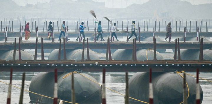 Los trabajadores caminan sobre un puente flotante en las orillas del río Ganges, antes del festival Maha Kumbh Mela en Prayagraj, India.