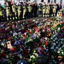 Miembros del cuerpo de bomberos de Magdeburgo se encuentran en un monumento improvisado fuera de la iglesia Johanniskirche (Iglesia de San Juan), cerca del lugar donde se produjo un atropello con un coche en un mercado navideño en Magdeburgo, este de Alemania. | Foto:JOHN MACDOUGALL / AFP